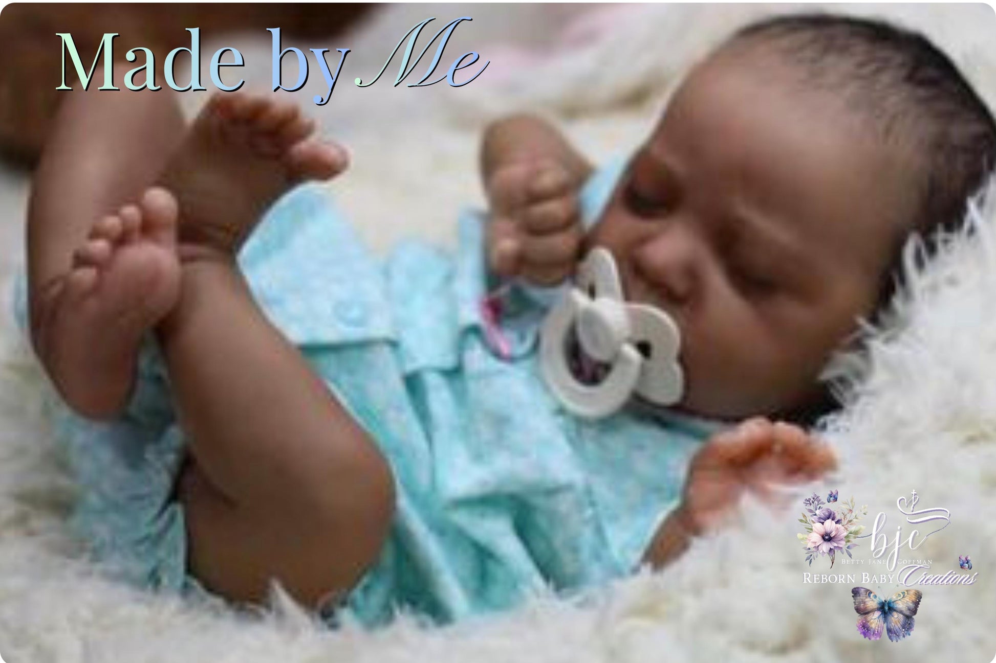 A newborn baby lying on a soft, fluffy surface, wearing a light blue outfit and holding a pacifier.