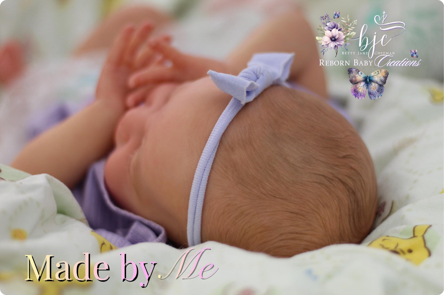 A newborn baby girl wearing a purple headband is lying on a bed with a floral patterned blanket.