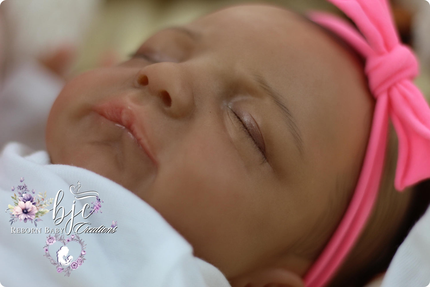 A close-up image of a sleeping baby with a pink headband, resting peacefully.
